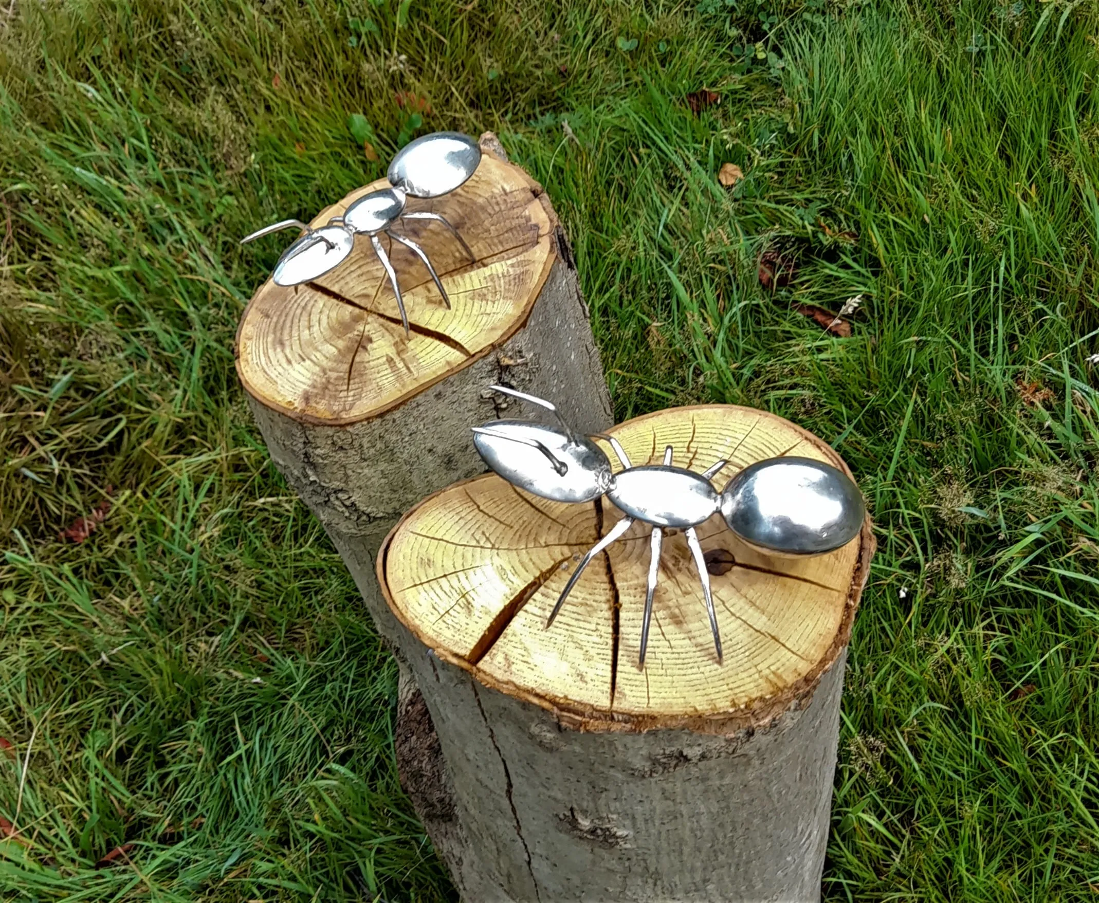 Zwei Ameisen aus Besteck auf Holzstämmen